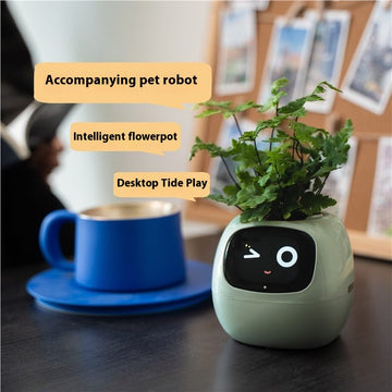Green robot-like flowerpot with a face on a desk next to a blue cup. Plant for desk.