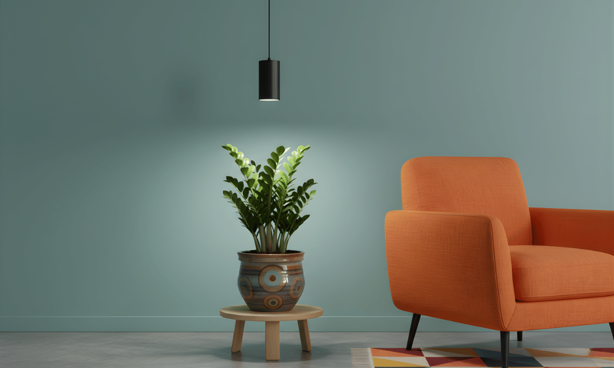 Orange armchair and potted plant and pendant grow light on a small table against a teal wall.