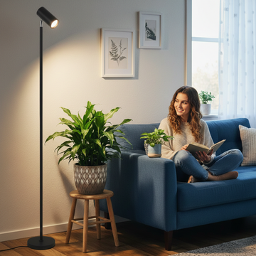 Woman reading a book on a blue couch in a cozy living room with plants and a floor grow light.