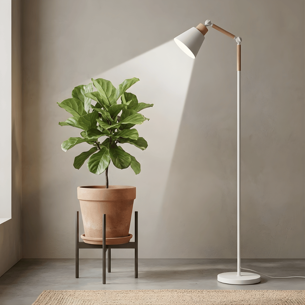 Floor grow light illuminating a potted plant against a neutral wall.
