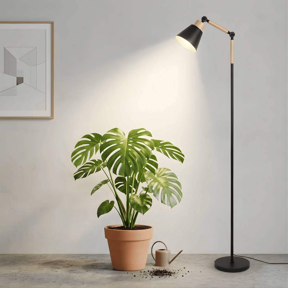 Floor grow light illuminating a potted plant in a room with a gray wall and framed picture.